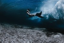 Female swimming under waves — Stock Photo