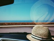 Chapeau de paille sur le tableau de bord de la voiture — Photo de stock