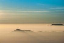 Mountains in fog at sunrise — Stock Photo