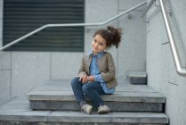 Souriante fille assise sur les marches — Photo de stock