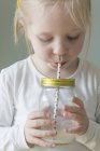 Девушка пьет молоко из банки — стоковое фото