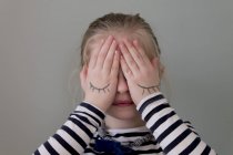 Chica cubriendo sus ojos con las manos - foto de stock