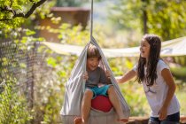 Garçon et fille jouer sur swing — Photo de stock