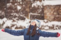 Девушка стоит в снегу и смотрит вверх — стоковое фото