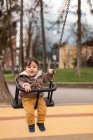 Мальчик на качелях на детской площадке — стоковое фото
