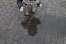 Girl looking at reflection in puddle — Stock Photo