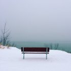 Скамейка на скале в снегу — стоковое фото