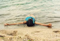 Bambina sdraiata tra le onde — Foto stock