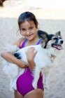 Menina abraçando cão na praia — Fotografia de Stock