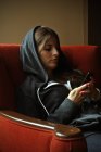 Женщина с помощью телефона сидя на диване — стоковое фото