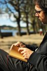 Man on bench looking at note pad — Stock Photo