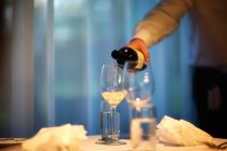 Uomo versando vino bianco in bicchiere da vino — Foto stock