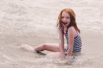 Сміючись дівчина сидить на пляжі — стокове фото