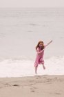 Girl running away from waves — Stock Photo