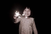 Girl holding sparkler outdoors — Stock Photo