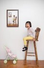 Giovane ragazza seduta su sgabello — Foto stock