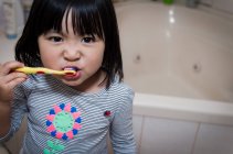 Chica cepillando dientes en el baño - foto de stock