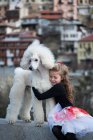 Chica abrazando gran caniche blanco - foto de stock