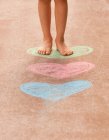 Girl standing on street chalk hearts — Stock Photo
