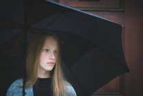 Chica de pie bajo el paraguas - foto de stock