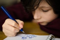 Junge zeichnet im Notizblock — Stockfoto