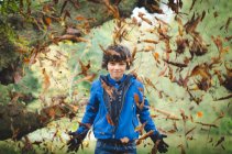Junge wirft Blätter weg — Stockfoto