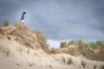 Хлопчик стоїть на трав'янистих дюнах — стокове фото