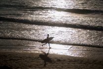 Серфер, бегущий по пляжу — стоковое фото
