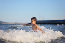 Мальчик ходит по морским волнам — стоковое фото