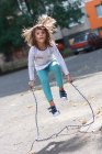 Маленькая девочка упражнения прыгать через веревку — стоковое фото