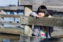 Chica apoyada contra barrera de madera - foto de stock
