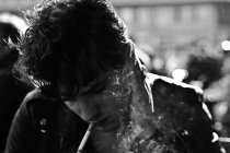 Jovem fuma cigarro no casaco — Fotografia de Stock