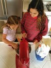 Hija ayudando a mamá en la cocina a cocinar - foto de stock