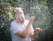 Rapaz a ser pulverizado com água — Fotografia de Stock