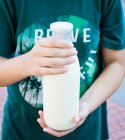 Niño sosteniendo en las manos botella de leche - foto de stock