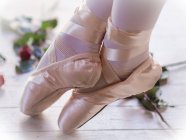 Girl in ballet shoes with feet crossed — Stock Photo