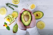 Mani con mezzo frutto di avocado — Foto stock