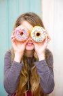 Chica mirando a través de donuts - foto de stock