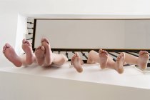 Gambe dei bambini appese attraverso ringhiere — Foto stock