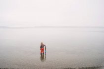 Мальчик стоит на мелководье в озере — стоковое фото