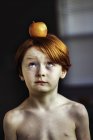 Хлопчик намагається збалансувати яблуко на голові — стокове фото