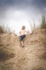 Мальчик лазает по песчаной дюне — стоковое фото