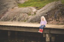 Girl sitting on wooden pier — Stock Photo