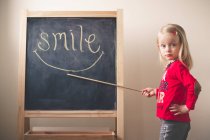 Маленькая девочка, указывающая на улыбку слова — стоковое фото