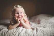 Sorrindo menina deitada na cama — Fotografia de Stock