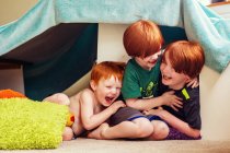 Three young brothers playing under tent — Stock Photo