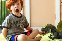 Молодий хлопчик грає з іграшковим динозавром — стокове фото