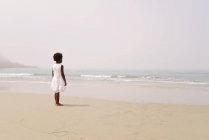 Дівчина на пляжі, що дивиться в море — стокове фото