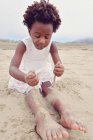 Fille assise sur la plage — Photo de stock
