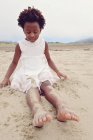 Fille assise sur la plage — Photo de stock